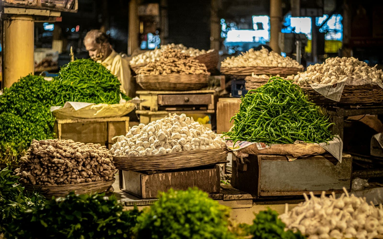 Woven baskets of garlic, ginger and green chillies at an Indian vegetable market stall at night